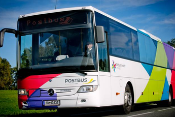 Postbus fährt auf einer Straße mit buntem Design und Fahrer sichtbar im Cockpit. | © Salzburger Verkehrsverbund GmbH