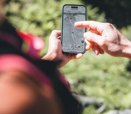 Hand mit Handy auf dem die App Nationalpark Erlebnis geöffnet ist. | © Ferienregion Nationalpark Hohe Tauern - Daniel Kogler