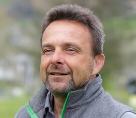 Mitarbeiter vom Nationalparkverwaltung Hohe Tauern in Salzburg im grauen Gilet vor grüner Naturkulisse. | © Nationalparkverwaltung Salzburg