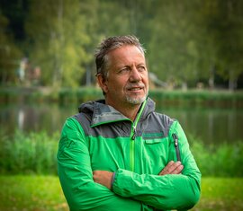 Mitarbeiter von der Nationalparkverwaltung Hohe Tauern in Salzburg, in Nationalparkjacke mit verschränkten Armen am See. | © NPHT / Glück