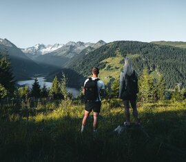 Zwei Wanderer genießen den Blick auf einen Stausee und Gletscher in den Alpen. | © Ferienregion Nationalpark Hohe Tauern - Daniel Kogler