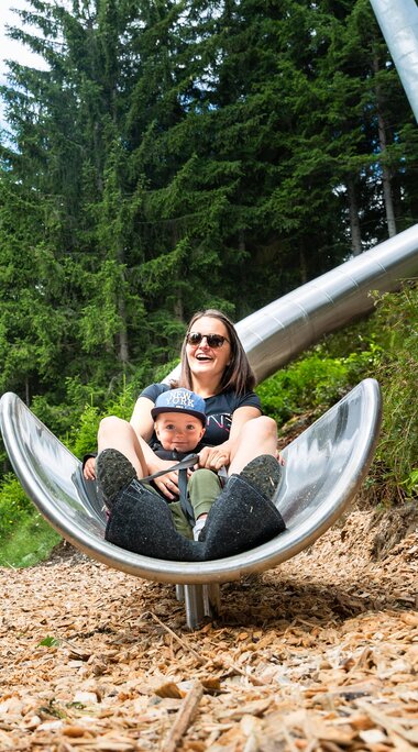 Mutter und Kind genießen gemeinsam eine Rutschfahrt auf einer großen Metallrutsche. | © Wildkogel-Arena Neukirchen & Bramberg