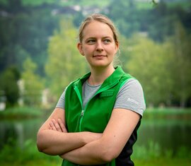 Frau in grüner Jacke vor einem See, nachdenklich in die Ferne blickend. | © Nationalparkverwaltung Salzburg