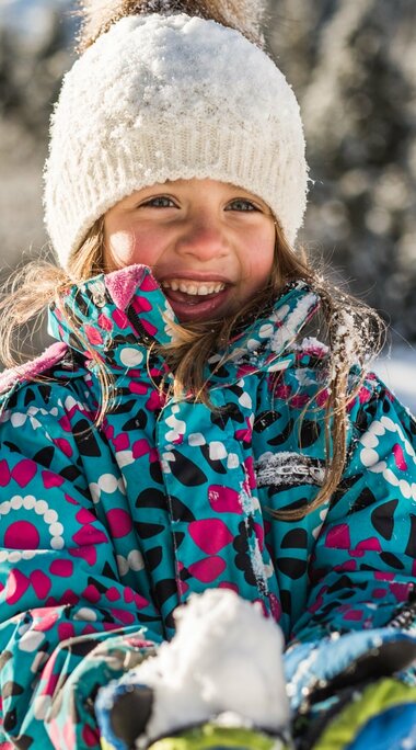 Lachendes Mädchen mit Schneeball im Winterwald. | © SalzburgLand Tourismus - Michael Größinger