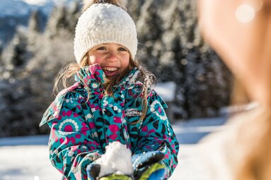 Lachendes Mädchen mit Schneeball im Winterwald. | © SalzburgLand Tourismus - Michael Größinger
