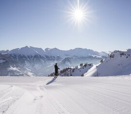 Langläufer auf frisch präparierter Loipe mit Sonne und Alpenpanorama. | © Ferienregion Nationalpark Hohe Tauern - Branislav Rohal