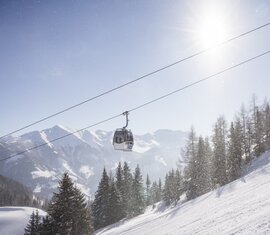 Gondelbahn fährt bei Sonnenschein über verschneiten Hang. | © Ferienregion Nationalpark Hohe Tauern - Branislav Rohal