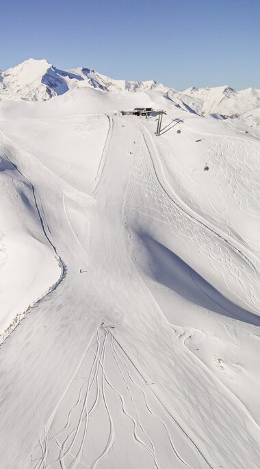 Verschneite Berglandschaft mit Skipiste und Spuren im Schnee. | © Ferienregion Nationalpark Hohe Tauern - Branislav Rohal