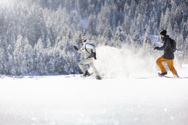 Zwei Personen rennen mit Schneeschuhen durch tiefen Schnee. | © Ferienregion Nationalpark Hohe Tauern - Daniel Breuer