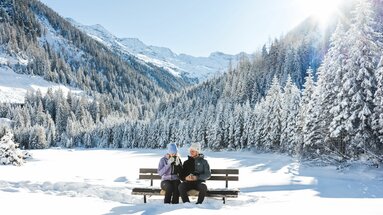 Zwei Menschen genießen den Winterausblick auf verschneite Berge. | © Ferienregion Nationalpark Hohe Tauern - Mathäus Gartner