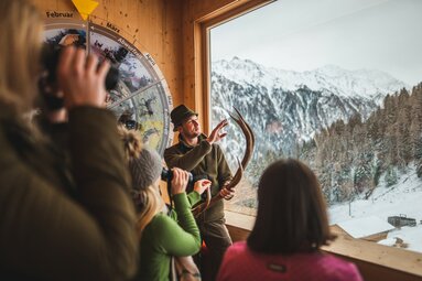 Ein Ranger erklärt mit Geweih vor Panoramafenster die Tierwelt im Winter. | © SalzburgLand Tourismus