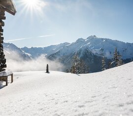 Winterliche Berghütte mit Blick auf sonnige, verschneite Alpenlandschaft. | © Ferienregion Nationalpark Hohe Tauern - Innerhofer