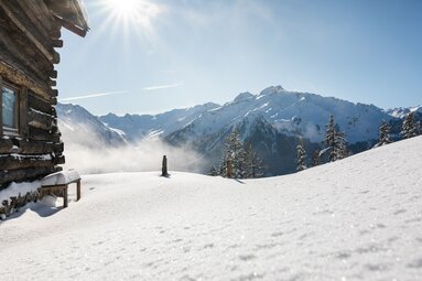 Winterliche Berghütte mit Blick auf sonnige, verschneite Alpenlandschaft. | © Ferienregion Nationalpark Hohe Tauern - Innerhofer