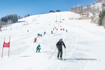 Skischüler fahren Slalom auf einer sonnigen, präparierten Piste. | © TVB Piesendorf Niedernsill - Harry Liebmann