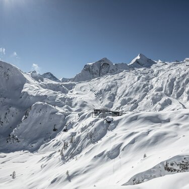 Schneebedeckte Alpenlandschaft mit Berggipfeln und klarblauem Himmel. | © Kitzsteinhorn