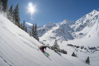 Skifahrer fährt bei Sonnenschein eine verschneite Bergpiste hinunter. | © Gasteinertal Tourismus GmbH - Oberschneider