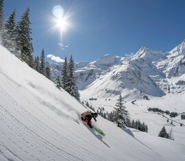 Skifahrer fährt bei Sonnenschein eine verschneite Bergpiste hinunter. | © Gasteinertal Tourismus GmbH - Oberschneider