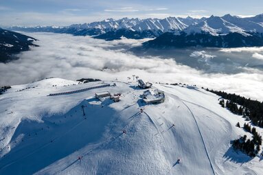 Skigebiet mit Liftstation über den Wolken inmitten verschneiter Alpenlandschaft. | © Mittersill Plus GmbH - Daniel Kogler