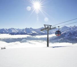 Rote Gondelbahn schwebt über Wolkendecke in den Alpen. | © Mittersill Plus GmbH - Michael Huber