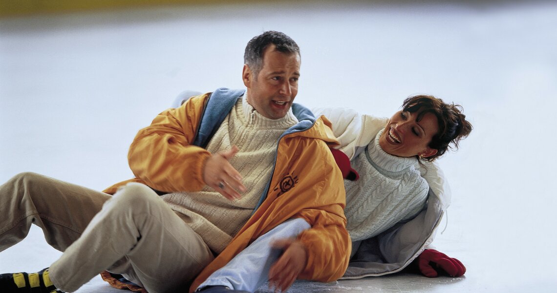 Couple laughing after falling on the ice rink | © Hohe Tauern National Park holiday region