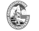 Logo der Großglockner Hochalpenstraße mit Oldtimer und Alpen. | © Großglockner Hochalpenstraßen AG
