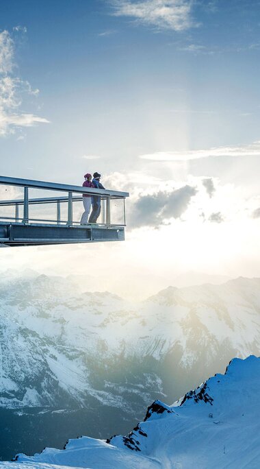 Aussichtspunkt mit Glasplattform über verschneiten Berggipfeln bei Sonnenuntergang. | © Kitzsteinhorn
