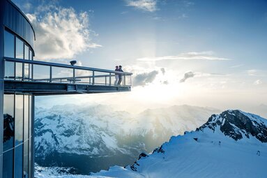 Aussichtspunkt mit Glasplattform über verschneiten Berggipfeln bei Sonnenuntergang. | © Kitzsteinhorn