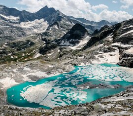 Türkisfarbener Gletschersee mit Eisplatten inmitten von schroffen Berggipfeln. | © Ferienregion Nationalpark Hohe Tauern