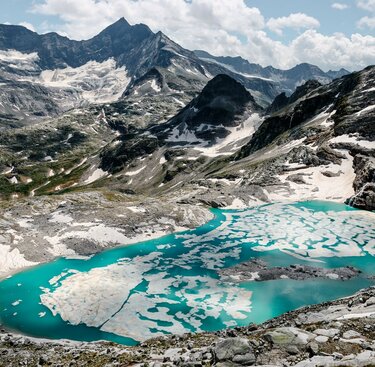 Türkisfarbener Gletschersee mit Eisplatten inmitten von schroffen Berggipfeln. | © Ferienregion Nationalpark Hohe Tauern