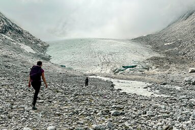 Wanderer auf steinigem Untergrund nähern sich einem Gletscher in dichtem Nebel. | © Ferienregion Nationalpark Hohe Tauern