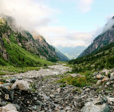 Weitläufiges Tal mit grünen Hängen, von Nebel und Bäumen umrahmt. | © Ferienregion Nationalpark Hohe Tauern